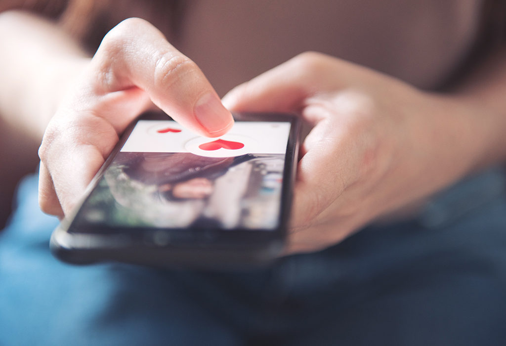 Finger of woman pushing heart icon on screen in mobile smartphone, onlinedating