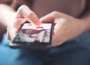 Finger of woman pushing heart icon on screen in mobile smartphone, onlinedating